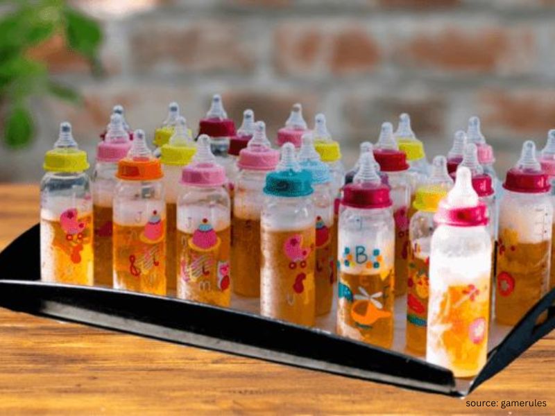 Adults laughing while competing in a baby bottle drinking game at a baby shower