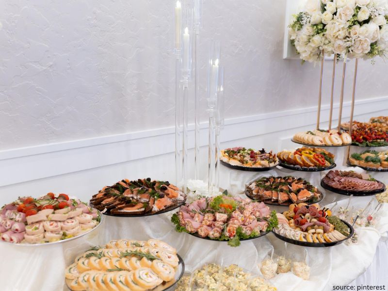 Beautifully styled wedding dessert and food table with candles and greenery decor.