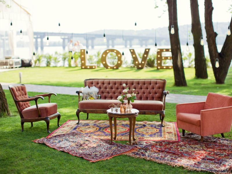 Cozy wedding lounge corner with candles, pillows, rugs, and soft seating for intimate wedding decor.