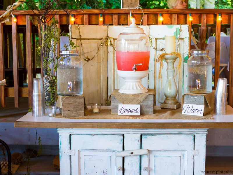 DIY wedding drink station with glass dispensers, greenery, and personalized signs for elegant budget wedding decor.
