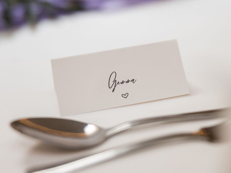 Minimal handwritten wedding place cards on textured paper for elegant intimate table decor.