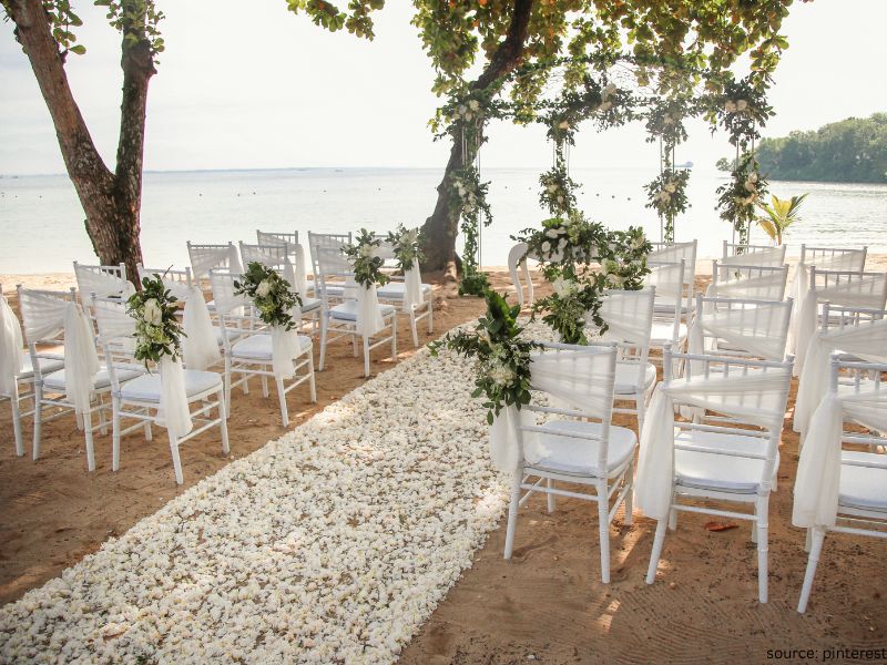 Romantic wedding aisle runner decorated with candles, petals, and greenery for a cozy ceremony setup.