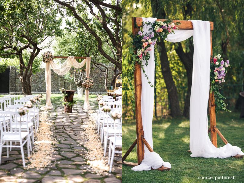 DIY backyard wedding ceremony arch with flowing fabric and greenery in an intimate outdoor setting.
