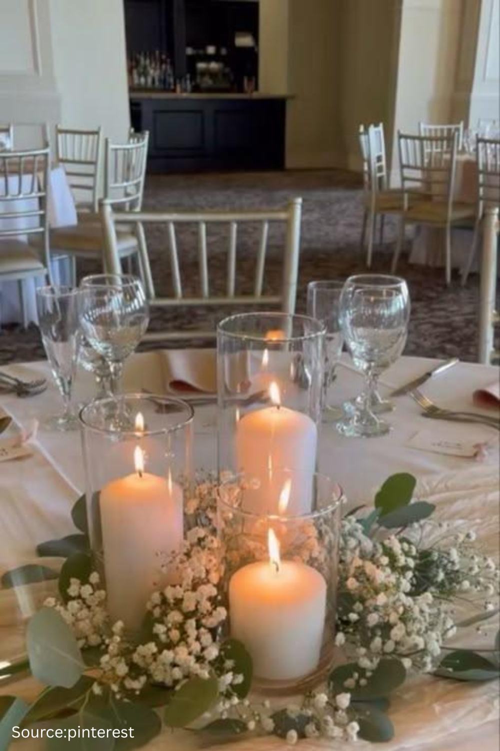 Romantic wedding centerpiece with pillar candles and minimal flowers creating an elegant soft-lit table setting.