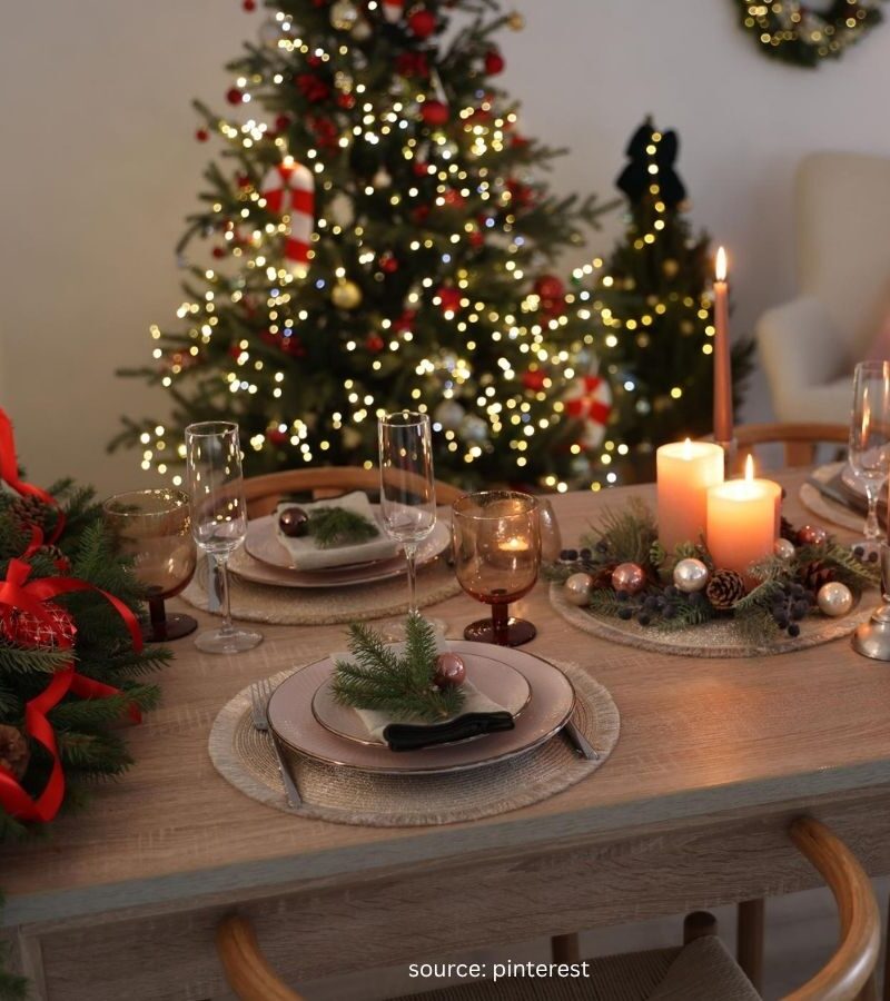 Cozy Christmas table setting with greenery, candles, and simple dinnerware.